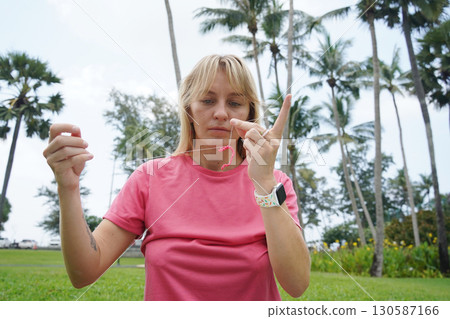Young woman beading colorful bracelets outdoors in a park Young woman beading colorful bracelets outdoors in a park 130587166