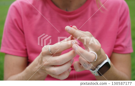 Young woman beading colorful bracelets outdoors in a park 130587177