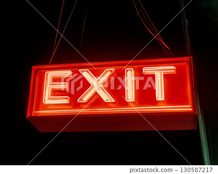 Bright red neon exit sign glowing in the dark  130587217