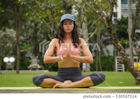 A young woman is joyfully practice a yoga mat in a beautiful park 130587314
