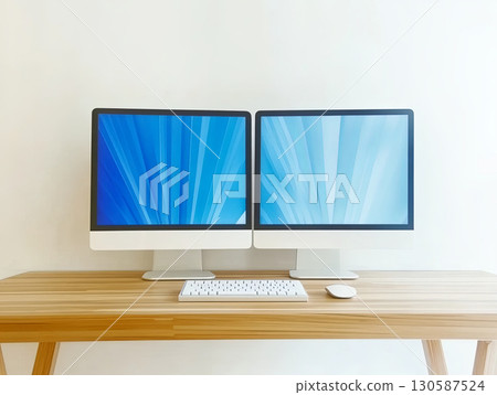 Dual computer monitors on a wooden desk with a keyboard and mouse 130587524