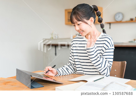 Elementary and junior high school girls waving at a tablet during a living room study Elementary and junior high school girls waving at a tablet during a living room study 130587688