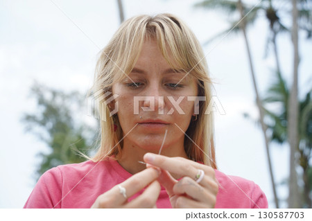 Young woman beading colorful bracelets outdoors in a park Young woman beading colorful bracelets outdoors in a park 130587703