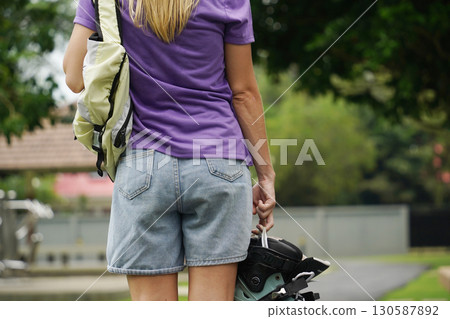 A woman is rollerblading gracefully on a road located in a park A woman is rollerblading gracefully on a road located in a park 130587892