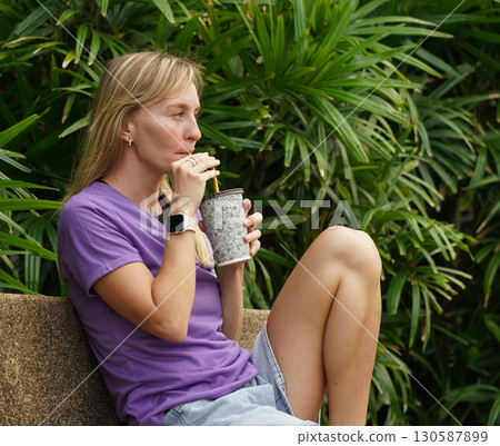 A woman is sitting on a bench and putting on her roller skates 130587899