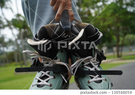 A woman is rollerblading gracefully on a road located in a park 130588059