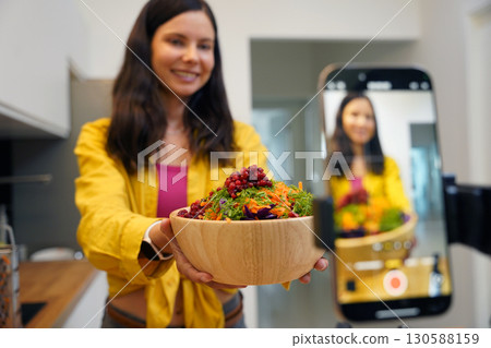 Young woman is broadcasting live from workshop how to prepare a vegetarian food Young woman is broadcasting live from workshop how to prepare a vegetarian food 130588159