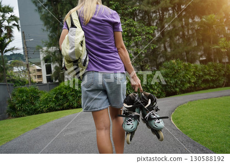 A woman is rollerblading gracefully on a road located in a park A woman is rollerblading gracefully on a road located in a park 130588192