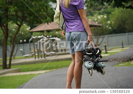 A woman is rollerblading gracefully on a road located in a park 130588320