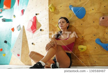 A strong female climber climbs an artificial wall with colorful grips 130588487