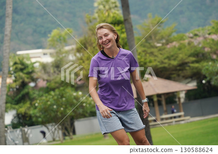 A woman is rollerblading gracefully on a road located in a park 130588624