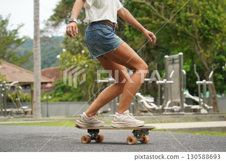 A young woman is skillfully riding a skateboard down a scenic park 130588693
