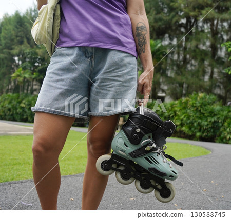 A woman is rollerblading gracefully on a road located in a park A woman is rollerblading gracefully on a road located in a park 130588745