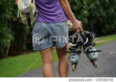 A woman is rollerblading gracefully on a road located in a park A woman is rollerblading gracefully on a road located in a park 130588746