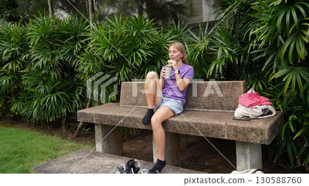 A woman is sitting on a bench and putting on her roller skates 130588760