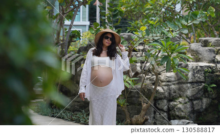 A pregnant woman is gracefully standing in front of a beautiful waterfall rock A pregnant woman is gracefully standing in front of a beautiful waterfall rock 130588817
