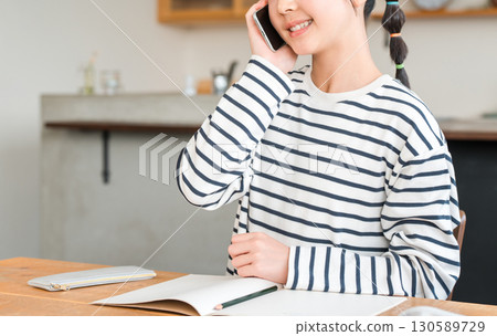 小學和中學的女生在家裡的客廳用智慧型手機聊天 小學和中學的女生在家裡的客廳用智慧型手機聊天 130589729
