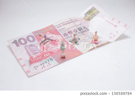 Miniature Figures Exercising on Hong Kong 100 Dollar Bill Surface 130589784