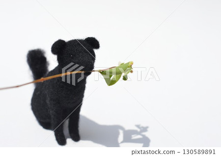 Felted wool dog holding a Symphoricarupos flower Felted wool dog holding a Symphoricarupos flower 130589891