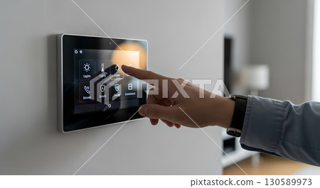 Hand interacting with smart home automation system displaying control interface panel on wall for 130589973