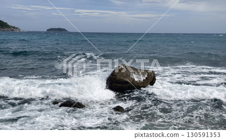 A tranquil beach scene featuring gentle waves lapping against rocks A tranquil beach scene featuring gentle waves lapping against rocks 130591353