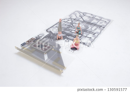 Miniature Figurines Practicing Yoga Posed on a Circuit Board 130591577