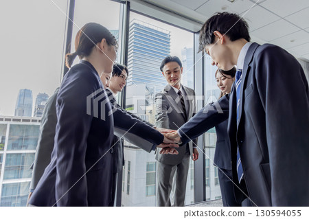 Business group standing in a circle with hands together Business group standing in a circle with hands together 130594055