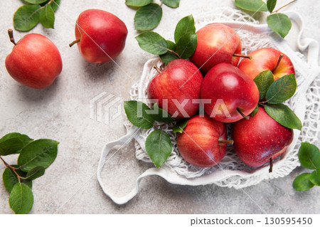 Fresh red apples with leaves in reusable shopping bag on table Fresh red apples with leaves in reusable shopping bag on table 130595450