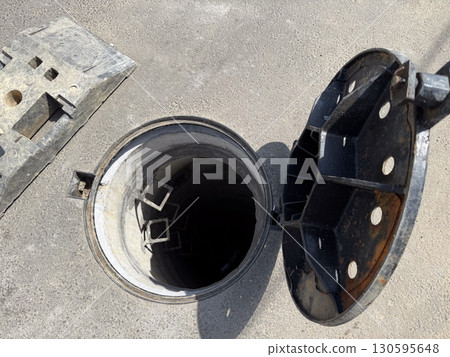 Open manhole on street with ladder. Infrastructure, safety, and city maintenance. 130595648
