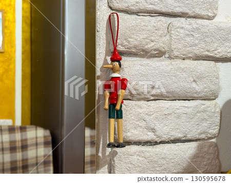 Wooden Pinocchio toy on the wall. Childhood nostalgia, culture and interior decoration. 130595678