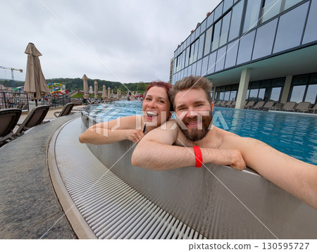 Happy couple embracing in outdoor pool. Love, relaxation, and joyful holiday moment. Happy couple embracing in outdoor pool. Love, relaxation, and joyful holiday moment. 130595727