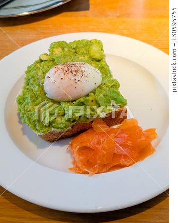 Close-up of avocado toast with poached egg and salmon. Healthy lifestyle, balanced diet, and nutritious gourmet meal. 130595755
