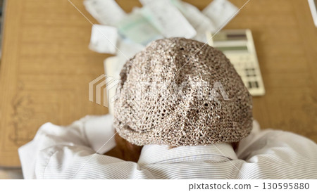 An elderly woman worried in front of a calculator and receipt _ rear An elderly woman worried in front of a calculator and receipt _ rear 130595880