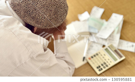An elderly woman worried in front of a calculator and receipt _ right facing diagonal An elderly woman worried in front of a calculator and receipt _ right facing diagonal 130595881