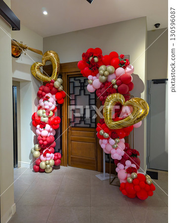 Golden heart balloons and colorful decorations form a festive arch at an entrance. Celebration, romance, holiday atmosphere and decorative culture in modern event lifestyle. 130596087