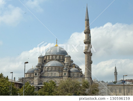 Exterior view of mosque with domes and minaret under blue sky. Religious architecture, history, and cultural heritage of Istanbul. 130596159