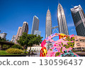 Vibrant traditional Wau Bulan moon kite with iconic Petronas Twin Towers and modern cityscape in the background, Kuala Lumpur, Malaysia. Clear blue sky, sunny day, Malaysian cultural heritage, KLCC 130596437
