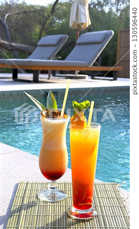 Vibrant cocktails resting on bamboo mat beside sparkling pool in luxurious desert resort, reflecting tropical leisure and summer relaxation. Vibrant cocktails resting on bamboo mat beside sparkling pool in luxurious desert resort, reflecting tropical leisure and summer relaxation. 130596440