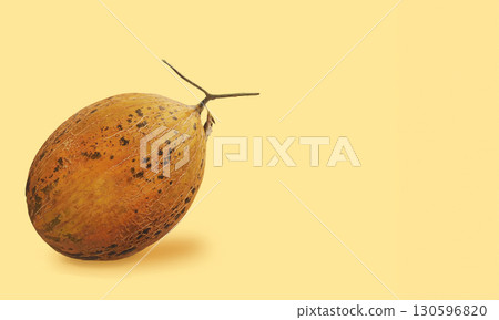 Orange oval melon fruit with textured skin resting on soft yellow background. Image with copy space Orange oval melon fruit with textured skin resting on soft yellow background. Image with copy space 130596820