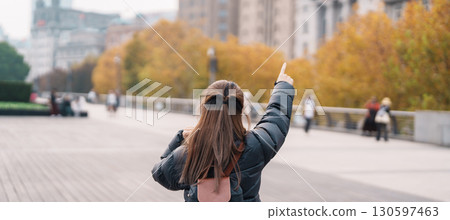 woman traveler visiting in Shanghai, China. Happy Female Tourist sightseeing Shanghai view in The Bund of Shanghai in Autumn season. landmark and popular for tourism attractions. Travel and Vacation 130597463