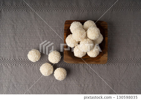 Coconut candies pile, coco ball. White truffle ball, indian ladoo or laddu with sweet cream and coco 130598035