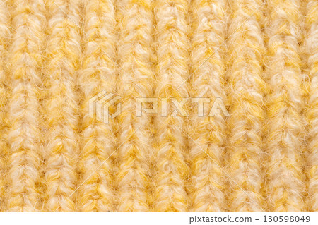 Knitted woolen fabric pattern in pale yellow. Macro texture of a sweater Knitted woolen fabric pattern in pale yellow. Macro texture of a sweater 130598049