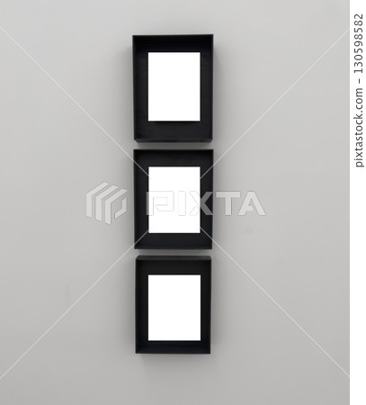 Three vertical black frames arranged in a column on a light wall. The frames are deep set, Three vertical black frames arranged in a column on a light wall. The frames are deep set, 130598582