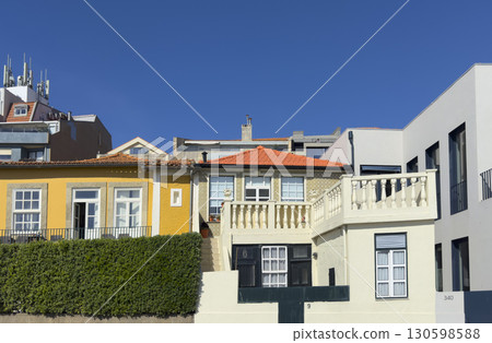 Row of colorful houses with traditional architecture, bright facades, red tiled roofs, and balconies 130598588