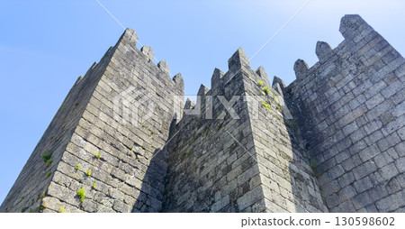 Close-up view of the medieval stone towers of Guimaraes Castle in Portugal, with crenellated Close-up view of the medieval stone towers of Guimaraes Castle in Portugal, with crenellated 130598602