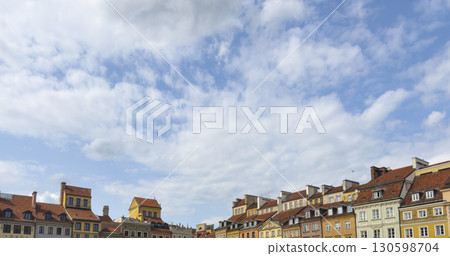 Panoramic view of Warsaw Old Town with colorful historic buildings under a wide cloudy sky. The 130598704