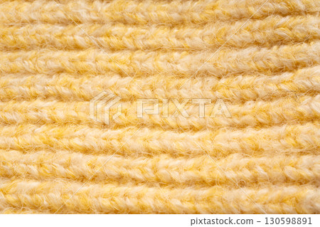 Knitted woolen fabric pattern in pale yellow. Macro texture of a sweater Knitted woolen fabric pattern in pale yellow. Macro texture of a sweater 130598891