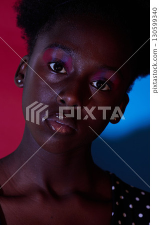 Trendy, aesthetic and portrait of black woman in dark color lighting isolated on a studio background. Neon, art and face of an African girl with creativity, makeup and stylish on a creative backdrop 130599340
