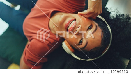 Smile, sofa and woman with headphones from above, relax and singing in living room with streaming radio. Music, energy and girl on couch in home listening to audio with internet, technology and fun 130599510