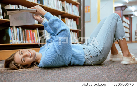 Portrait, woman on floor and reading in library, relax and learning with smile, hobby or higher education. Female student girl or lady with book, knowledge or college research for studying and campus 130599570